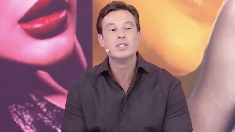 Gabriel Cartolano fala durante o Fofocalizando com telão colorido ao fundo no estúdio do SBT.