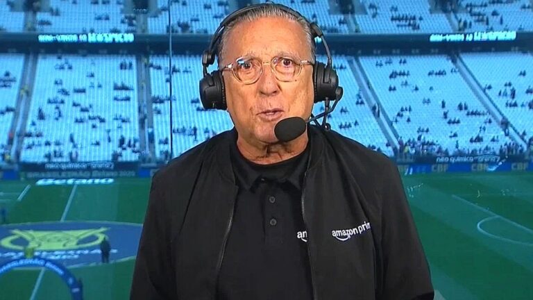 Galvão Bueno usa headset durante transmissão esportiva em estádio com logo do Amazon Prime Video