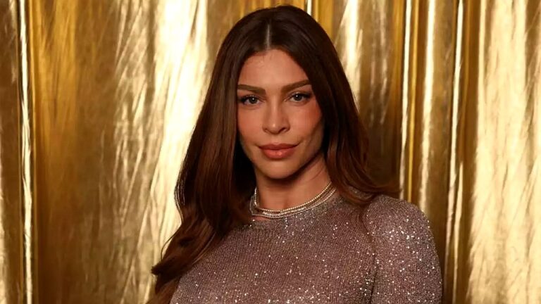Grazi Massafera posa com vestido brilhante diante de fundo dourado em evento de moda