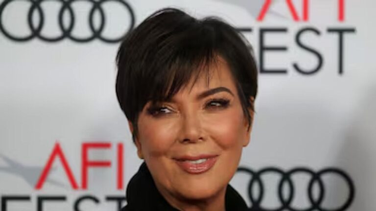 Mulher de cabelo curto posa em evento com logotipos do AFI Fest e da Audi ao fundo