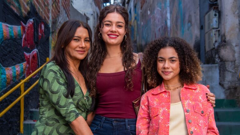 Ligia, Gerluce e Joélly posam abraçadas em viela da comunidade em cena da novela Três Graças
