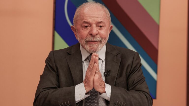 Luiz Inácio Lula da Silva com mãos unidas durante participação no programa Sem Censura em cenário colorido da TV Brasil