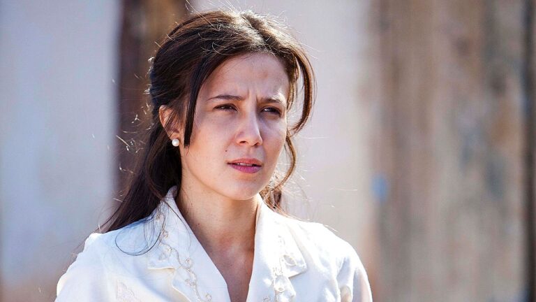Marjorie Estiano com expressão séria em cena de novela da Globo ao ar livre