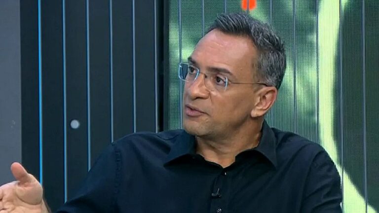 Homem de camisa preta e óculos fala durante entrevista em estúdio de programa jornalístico