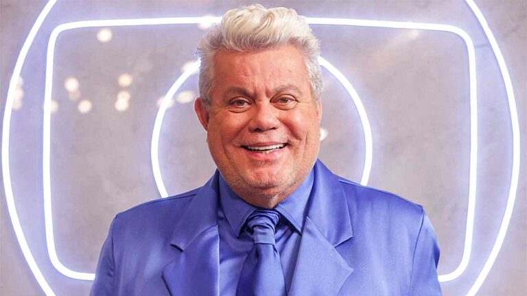 Milton Cunha usando terno azul em foto promocional diante de cenário iluminado com símbolo da Globo