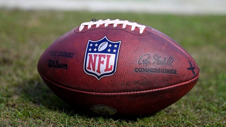 Bola de futebol americano da NFL sobre gramado com logotipo da liga em destaque
