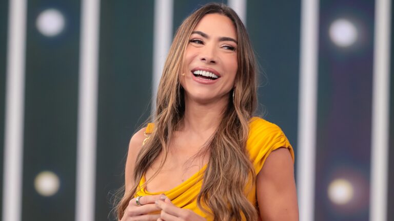Patricia Abravanel sorri durante apresentação de programa do SBT usando vestido amarelo.