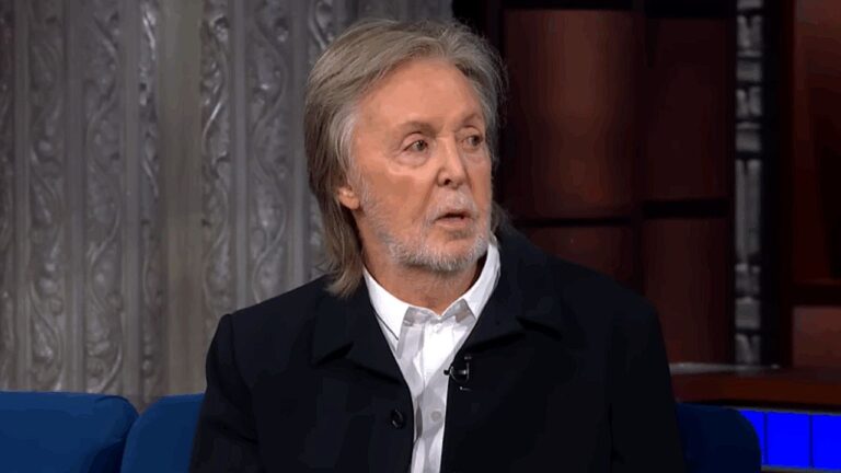 Paul McCartney durante entrevista em programa de televisão com blazer escuro e cabelo grisalho