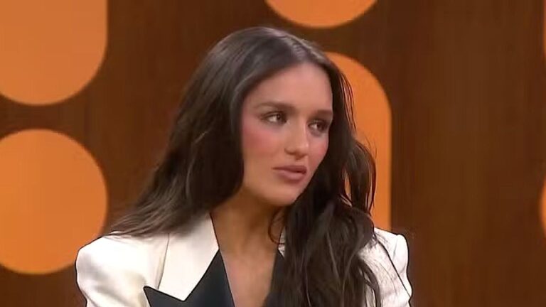 Rafa Kalimann participa de entrevista em programa de TV com blazer branco e fundo laranja