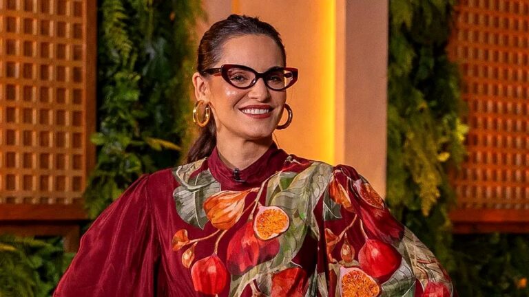 Chef Renata Vanzetto sorri em estúdio de programa culinário usando vestido estampado e óculos de armação vermelha