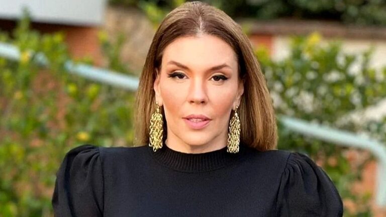 Mulher de vestido preto e brincos dourados posa ao ar livre em foto para entrevista ou programa de TV