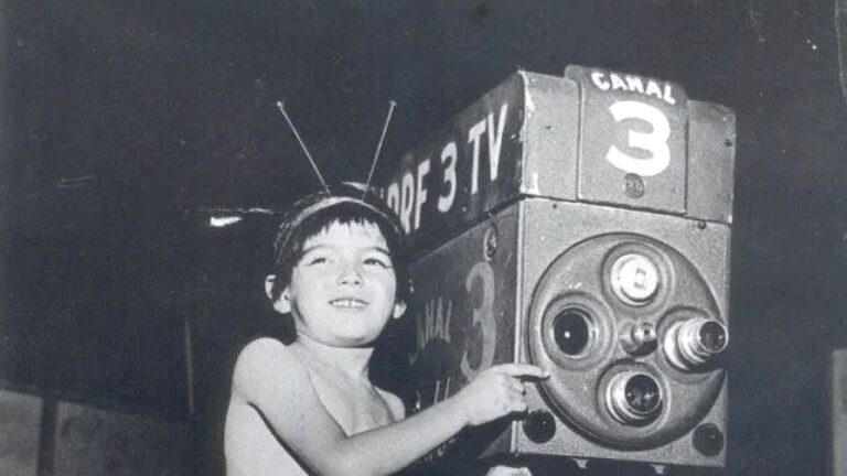 Criança posa ao lado de câmera da TV Tupi com identificação do Canal 3 em foto histórica