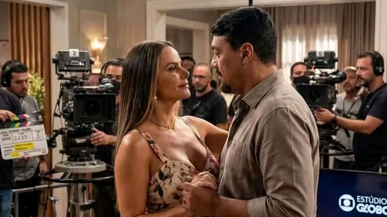 Homem e mulher gravam cena romântica com equipe de produção ao fundo nos bastidores da Globo