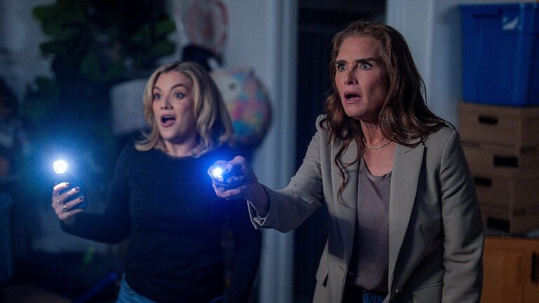 Brooke Shields e jovem investigadora apontam lanternas com expressão de choque em cena de série de suspense