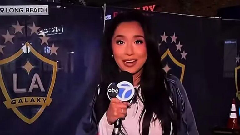 Repórter da ABC7 segura microfone durante entrada ao vivo em frente ao painel do LA Galaxy em Long Beach