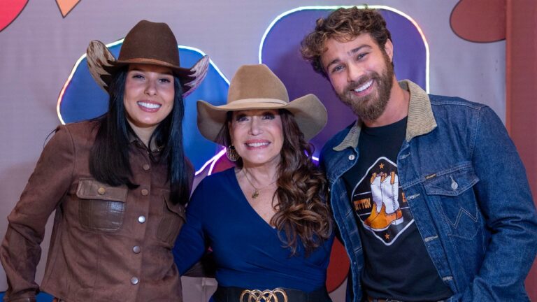 Ana Castela de chapéu e jaqueta marrom posa sorrindo entre Suzana Vieira e André Luiz Frambach em divulgação de Onde Está a Boiadeira?
