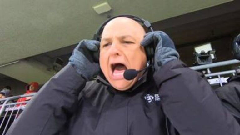 André Henning reage durante transmissão esportiva com headset e agasalho em cabine de narração de estádio
