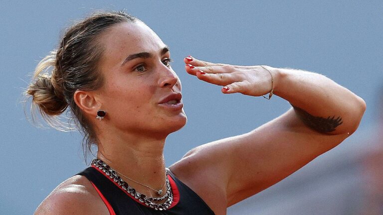 Aryna Sabalenka celebra ponto durante partida de tênis com gesto de saudação à torcida em quadra profissional