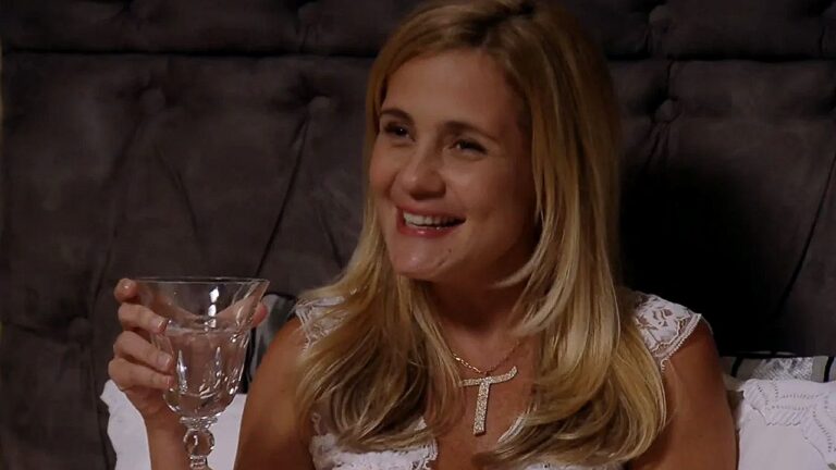 Carminha (Adriana Esteves) sorri com taça na mão em cena da novela Avenida Brasil
