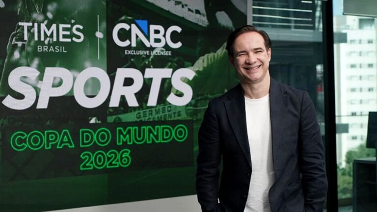 Celso Cardoso posa ao lado de painel do Times Brasil CNBC Sports com destaque para a Copa do Mundo de 2026