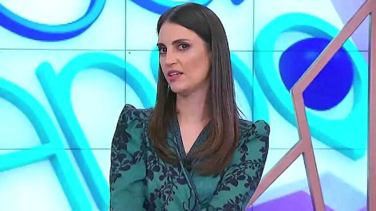Chris Flores durante apresentação de programa de TV usando blusa verde estampada no estúdio da emissora