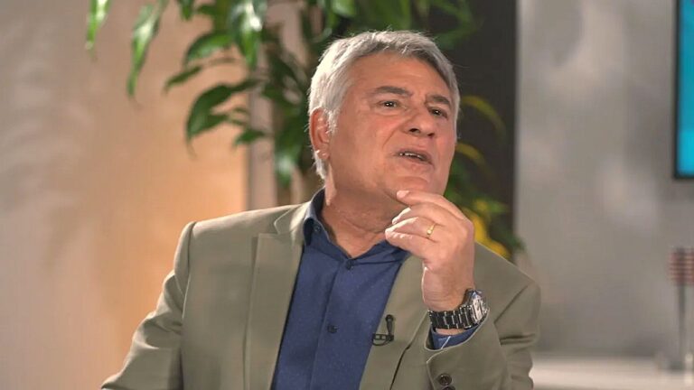 Cleber Machado comenta durante entrevista em estúdio de televisão com gesto de reflexão e olhar atento