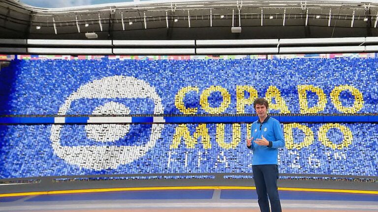 Apresentador no estúdio da Globo diante do telão com identidade visual da cobertura da Copa do Mundo