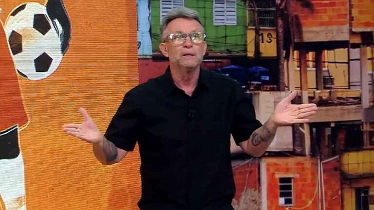 Craque Neto gesticula durante apresentação de programa esportivo com cenário de futebol ao fundo