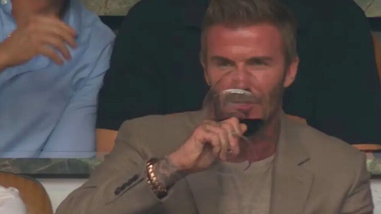 David Beckham assiste a partida de futebol enquanto segura taça de vinho na arquibancada do torneio