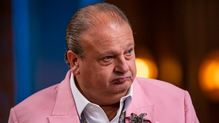 Erick Jacquin de blazer rosa com expressão séria durante avaliação em programa de culinária