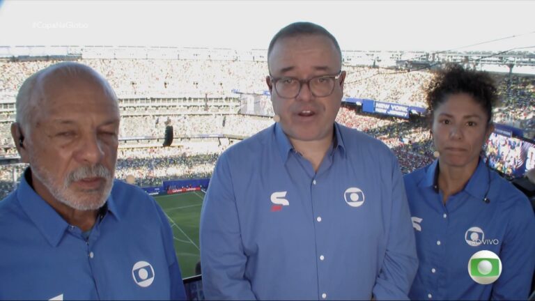 Everaldo Marques ao centro com equipe da Globo na cabine de transmissão diante de estádio lotado em Brasil x Marrocos, em jogo válido pela Copa do Mundo
