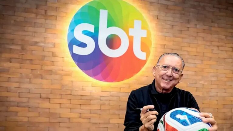 Galvão Bueno segura bola de futebol diante do logotipo do SBT em imagem de divulgação da emissora