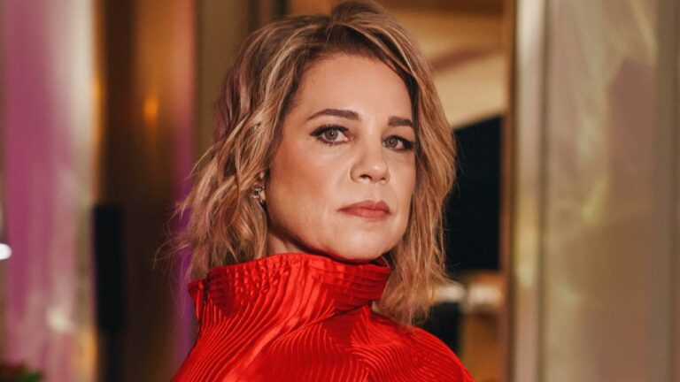 Isabel Teixeira de vestido vermelho com gola alta posa para foto no lançamento da novela Quem Ama Cuida