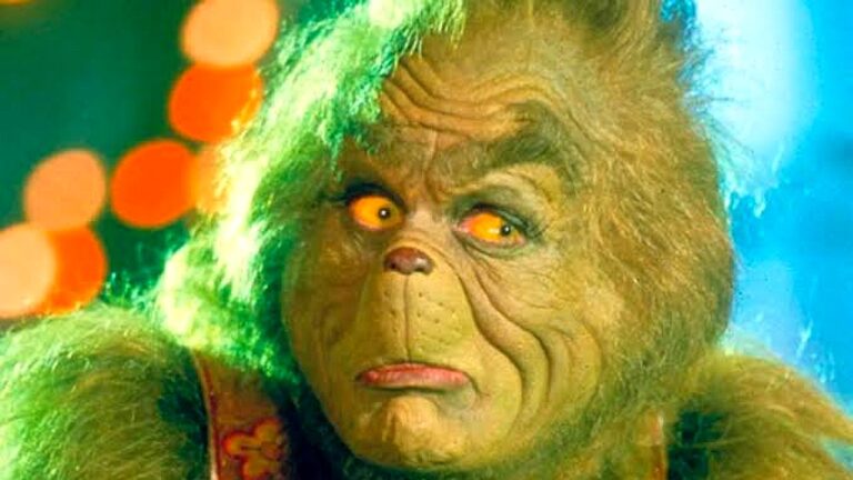 Grinch com expressão séria e olhos amarelos brilhantes em cena do filme Como o Grinch Roubou o Natal