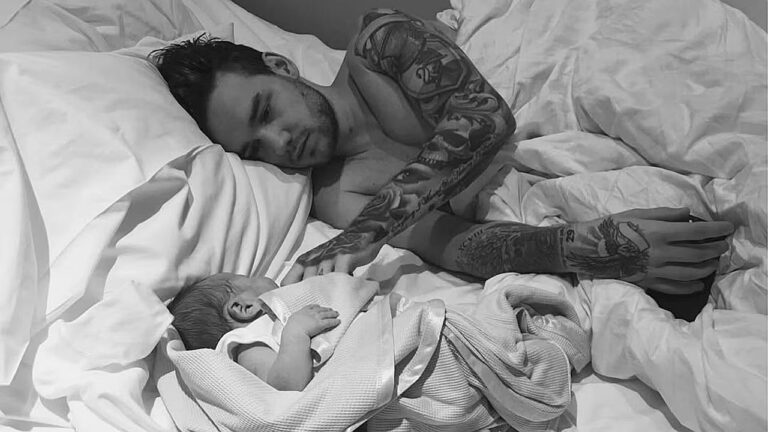 Liam Payne deitado na cama observando o filho recém-nascido envolto em manta em registro compartilhado nas redes sociais