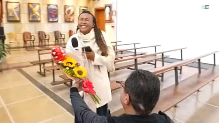 Pessoa ajoelhada entrega buquê de flores durante pedido de casamento em igreja com bancos ao fundo