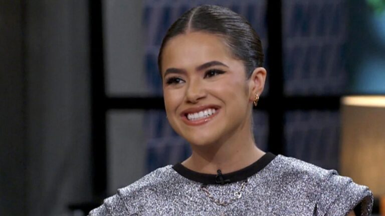 Maisa Silva sorri durante entrevista em programa de televisão com cabelo preso e figurino prateado brilhante