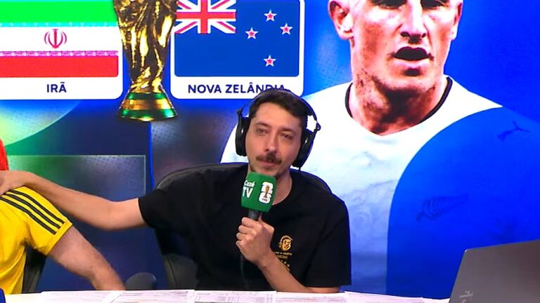 Marcelo Hazan comenta partida de futebol em transmissão esportiva com painel da Copa do Mundo ao fundo
