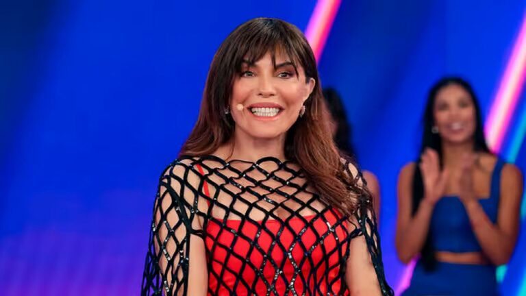 Márcia Goldschmidt sorri no palco durante apresentação de programa ao vivo com plateia ao fundo no SBT