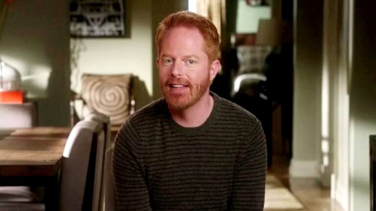 Jesse Tyler Ferguson fala à câmera em sala de estar durante depoimento na série Modern Family