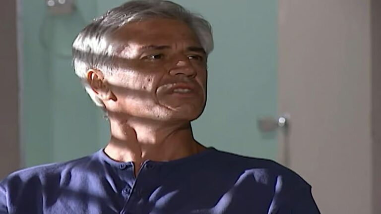 Nuno Leal Maia com expressão séria em cena de novela enquanto conversa em ambiente interno iluminado pelo sol