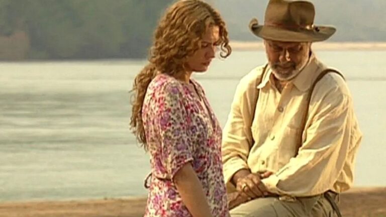 Mulher e fazendeiro conversam à beira do rio em cena da novela O Rei do Gado