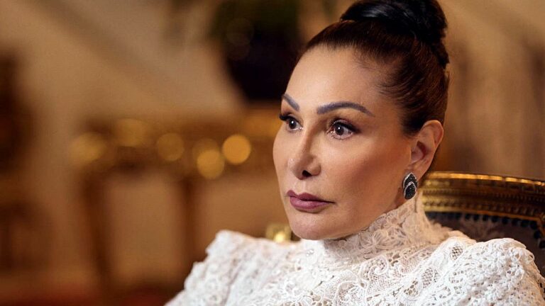 Mulher com vestido rendado branco e expressão séria em cena do filme O Testamento