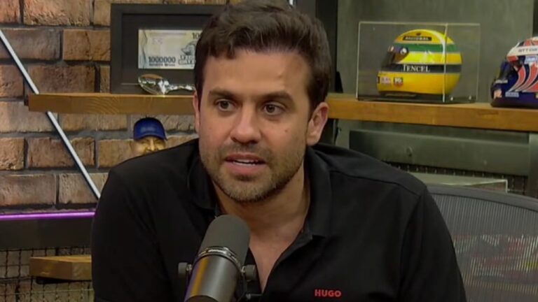 Pablo Marçal fala ao microfone durante entrevista em estúdio com prateleiras ao fundo e capacete de Ayrton Senna em exposição