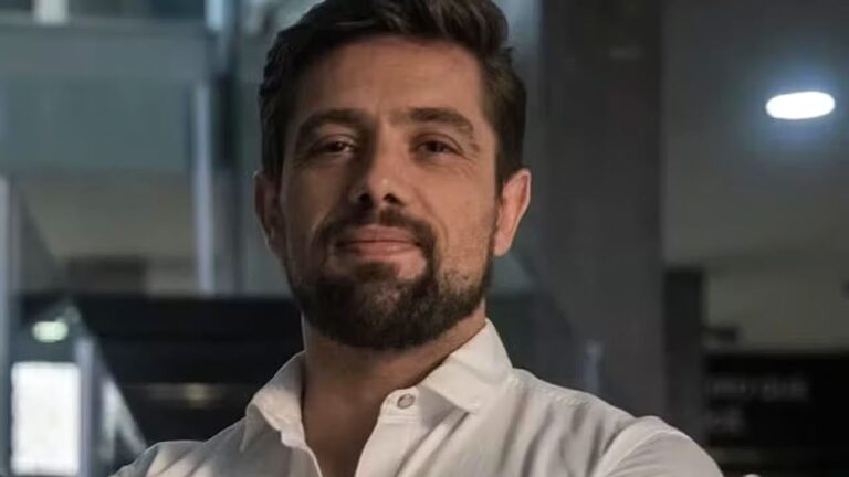 Rafael Cardoso de camisa branca posa em ambiente corporativo em foto de divulgação do ator