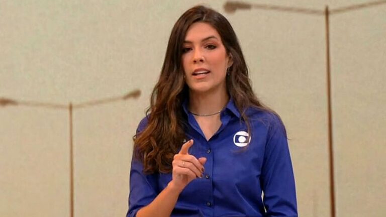 Renata Silveira aponta para a câmera durante chamada institucional da TV Globo em estúdio de gravação