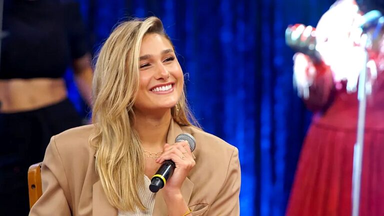 Sasha Meneghel sorri com microfone na mão durante participação em programa de televisão