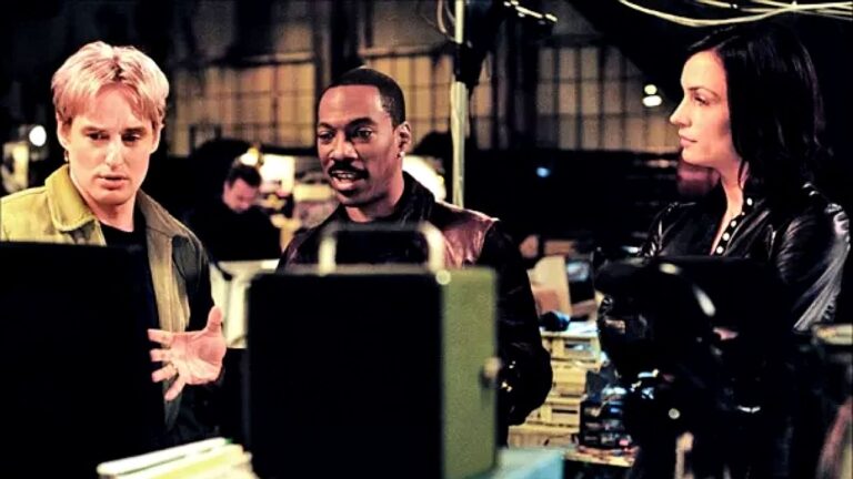 Owen Wilson, Eddie Murphy e personagem de Charlize Theron analisam monitor em cena do filme Sou Espião