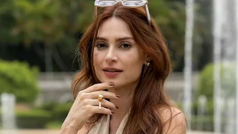 Thaila Ayala com cabelos ruivos e óculos sobre a cabeça durante conversa em área externa arborizada