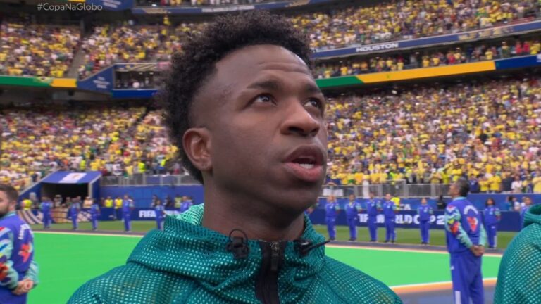 Vini Jr. durante o hino nacional antes de Brasil x Japão com torcida ao fundo no estádio pela Copa do Mundo